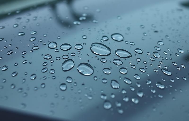 Gouttes d'eau perlant sur un pare-brise traité avec un produit hydrophobe anti-pluie